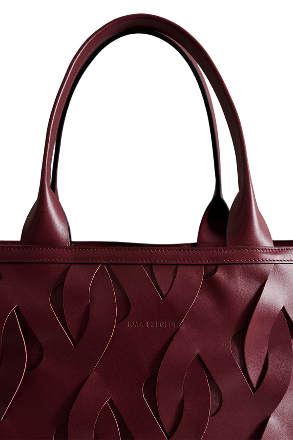 Close-up view of a Kata Szegedi Woven leather tote bag in burgundy, shown against a plain white background.