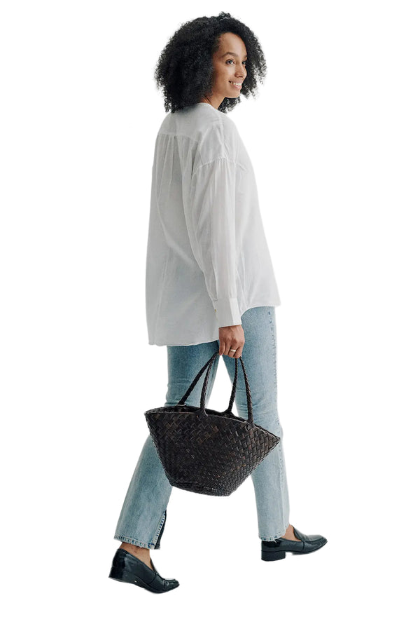 Rear view of a woman wearing Dragon Diffusion woven leather tote bag in dark brown, paired with white shirt, washed blue jeans and black loafers, shown against a plain white background.