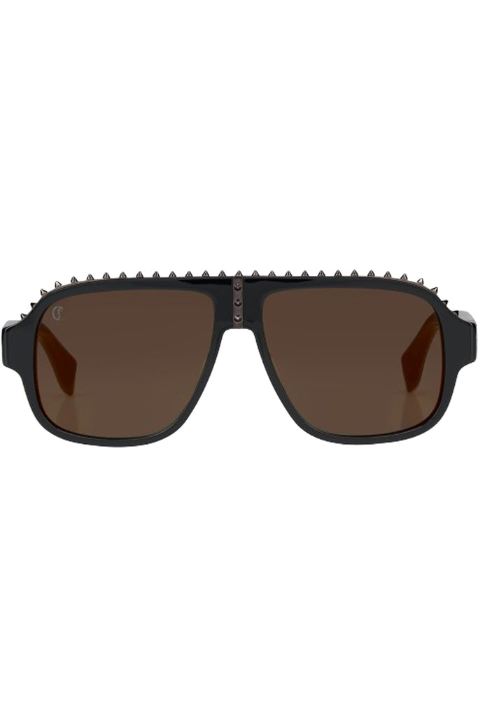 Christian Louboutin moto sunglasses in dark brown with black frame and spiny details, shown against a plaid white background.