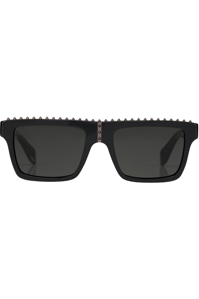Christian Louboutin sunglasses in gray with black frame and spiny details, shown against a plaid white background.
