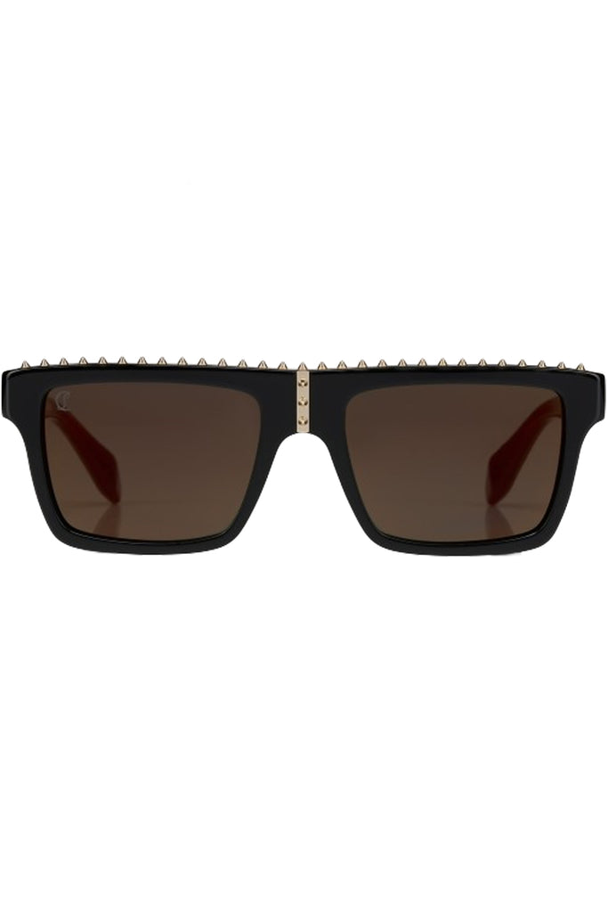 Christian Louboutin sunglasses in dark brown with black frame and spiny details, shown against a plaid white background.