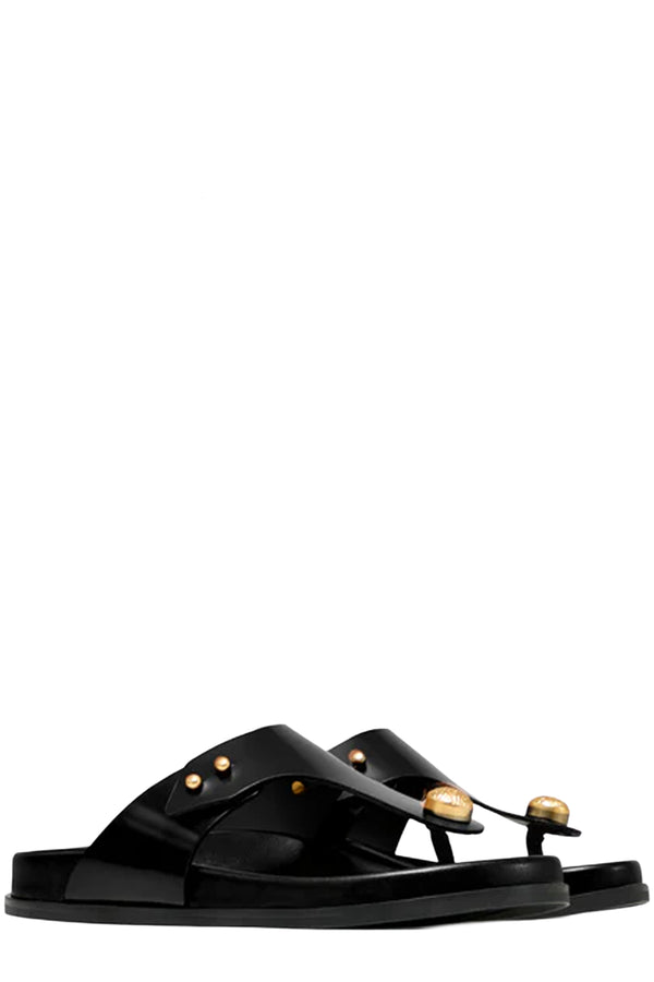 Rotated view of a pair of Vanda Novak flat sandals in glossy black made from leather with golden details, shown against plaid white background.