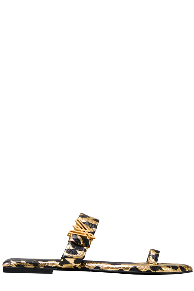 Vanda Novak flat sandal in gold and black with a golden logo made from leather, shown against plaid white background.