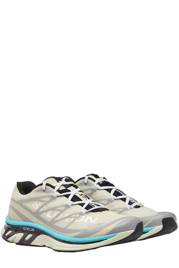 Rotated view of a pair of MM6 Maison Margiela sneakers in beige, dark purple, silver with light blue touch, shown against a plain white background.