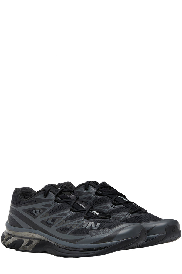 Rotated view of a pair of MM6 Maison Margiela sneakers in black with grey touch, shown against a plain white background.